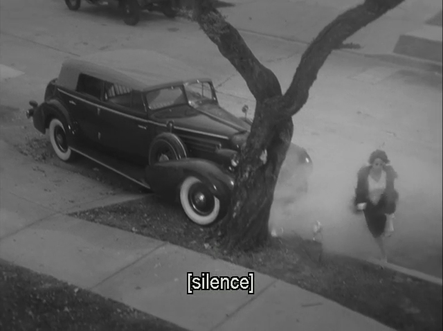 A frame from The Artist showing smoke billowing from a Cadillac that has hit a tree, with a silence caption.