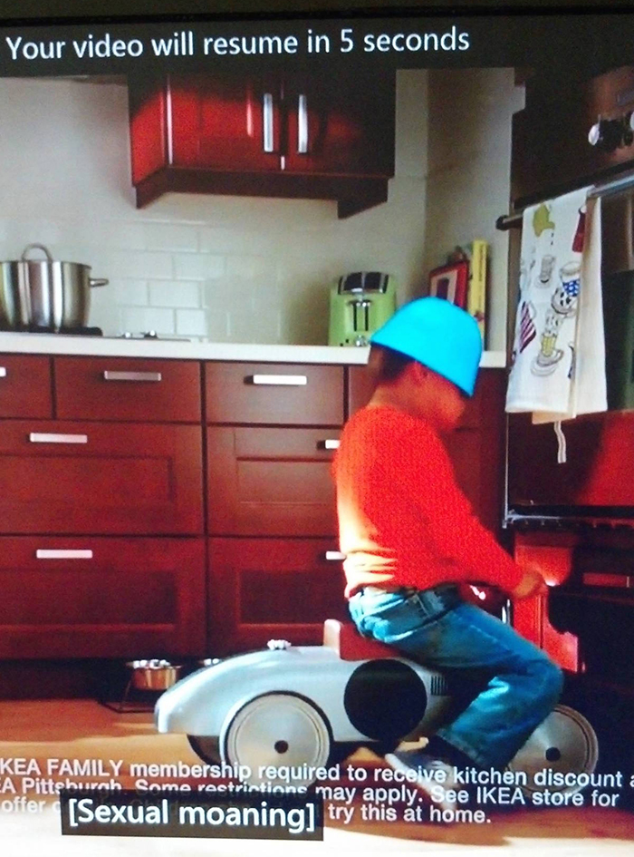 A frame from an Ikea commercial featuring a young boy riding a child's trike. A caption from the previous program lingers on the screen: [Sexual moaning]