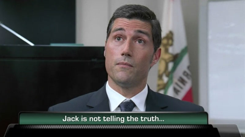 A frame from an enhanced episode of Lost. A close up of Jack, wearing a dark suit, seated with the California flag behind him. He's most likely in a courtroom.